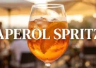 Aperol Spritz italiano con fetta d’arancia e cubetti di ghiaccio servito in terrazza