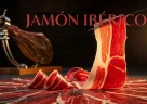 Fette sottili di jamón ibérico spagnolo con marmorizzazione visibile su un tagliere di legno