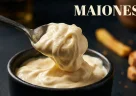 Maionese cremosa sollevata da un cucchiaio con consistenza densa, liscia e invitante in primo piano