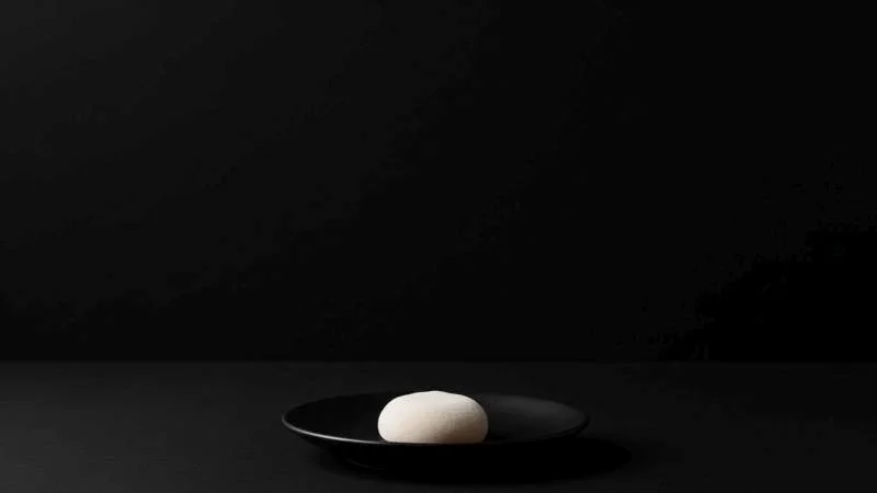 Singolo mochi isolato in spazio scuro come simbolo di rispetto e cautela