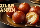 Gulab jamun indiani immersi in sciroppo dolce, palline dorate e lucide su superficie chiara