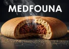 Medfouna marocchina tagliata a fette con ripieno speziato all'interno del pane, su un piatto tradizionale