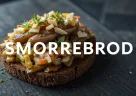 Smørrebrød danese: pane di segale con aringa marinata, uovo sodo e cetriolini, disposti con ordine secondo la tradizione nordica