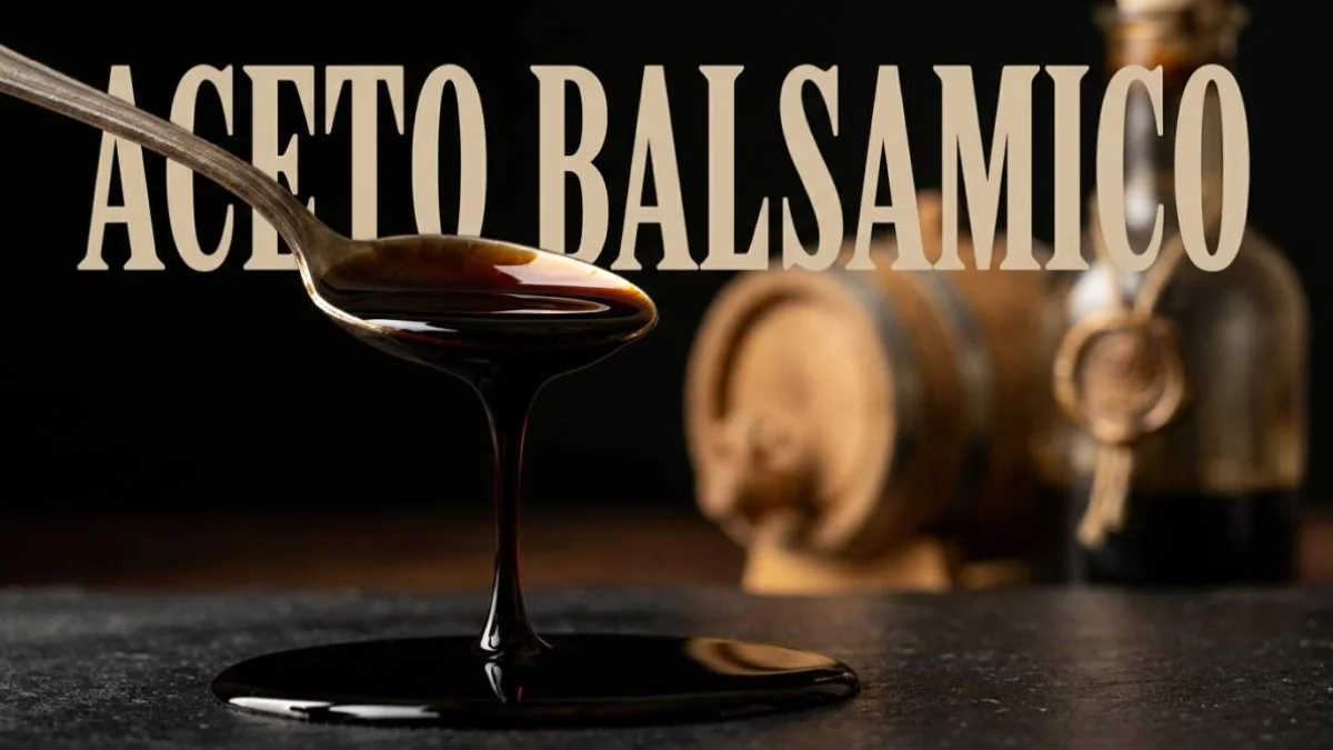 Goccia di aceto balsamico invecchiato che cade lentamente accanto a botti di legno
