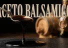 Goccia di aceto balsamico invecchiato che cade lentamente accanto a botti di legno