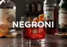 Cocktail Negroni rosso servito con ghiaccio e fetta d’arancia in un bicchiere elegante